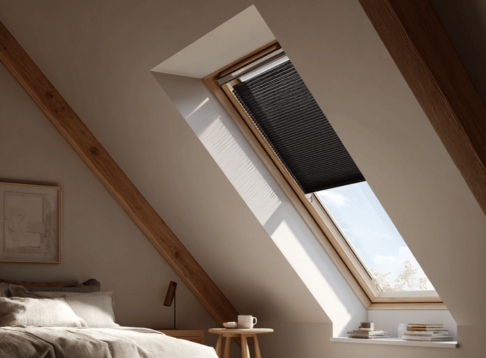 Slaapkamer met dakraam met zwarte verduisterende plisségordijnen. 